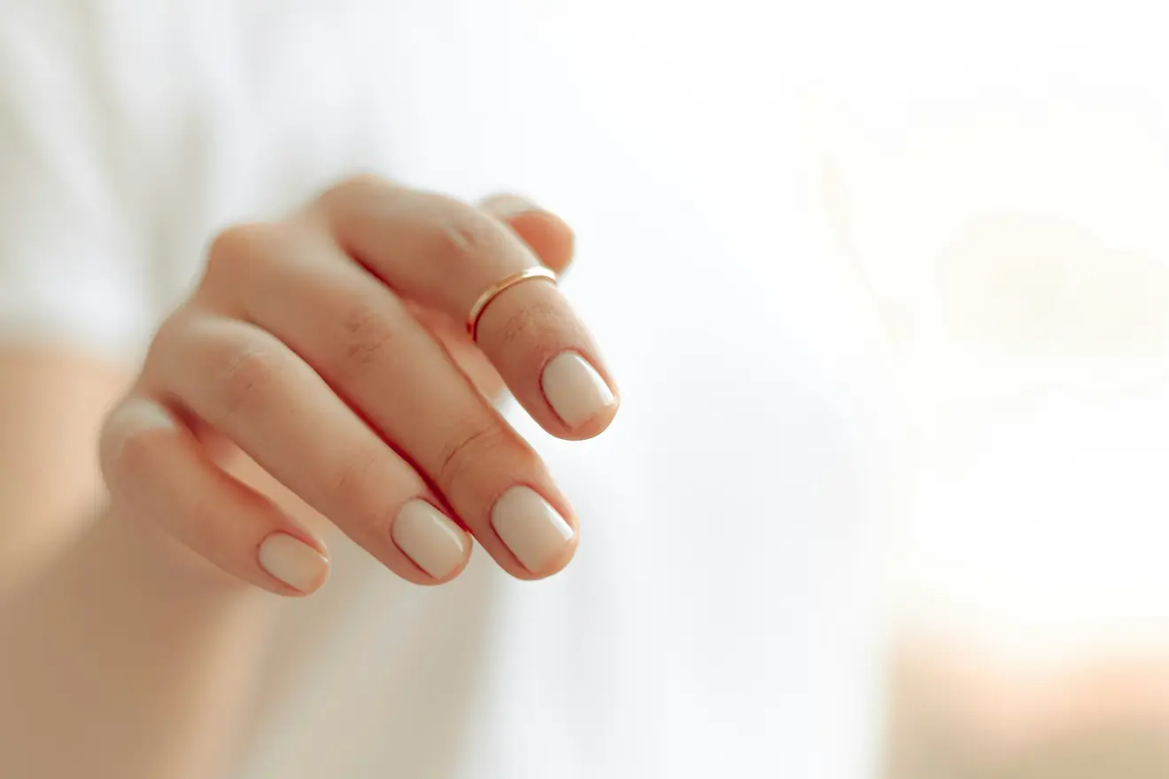 Hand mit hellem Naturnagellack