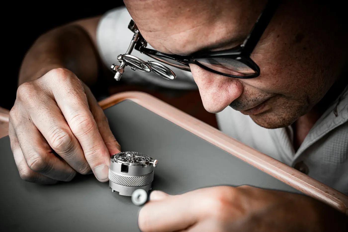 Uhrmacher mit Lupenbrille prüft ein offenes mechanisches Uhrwerk